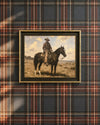 The Horseman framed cowboy painting hung on a navy, rust, and cream plaid wall